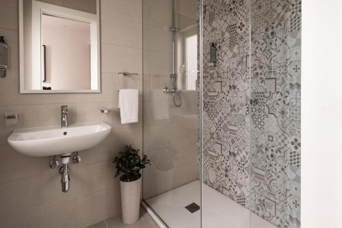 a bathroom with a sink and a glass shower at Urban Isle in Il-Gżira