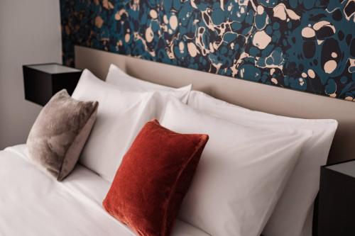a white bed with two red pillows on it at Urban Isle in Il-Gżira