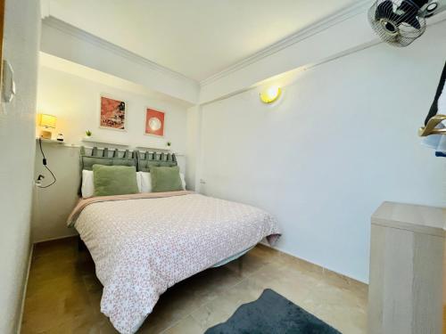 - une petite chambre avec un lit et des oreillers verts dans l'établissement Apartamento Mar y Montaña, à Cullera