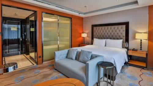 Changzhou Yuanzhou Hotel في تشانغتشو: غرفه فندقيه بسرير واريكه