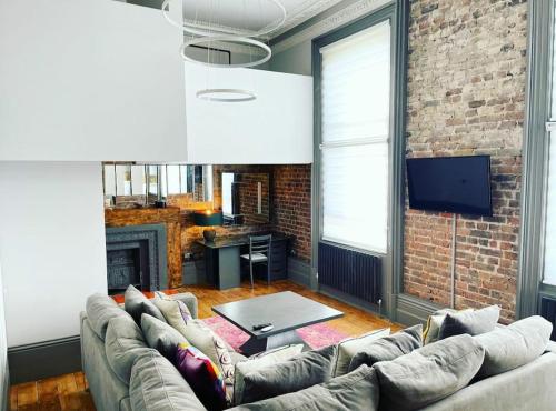 a living room with a couch and a brick wall at 22 Stunning Large Loft - Great Location - Free Onsite Parking - Garden View- Quiet in Brighton & Hove