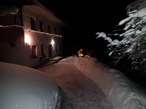 a snow covered road next to a building at night at Miklavževa hiša with a bread oven in Železniki