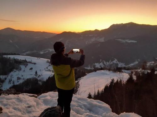 a man taking a picture of the sunset on a mountain at Miklavževa hiša with a bread oven in Železniki