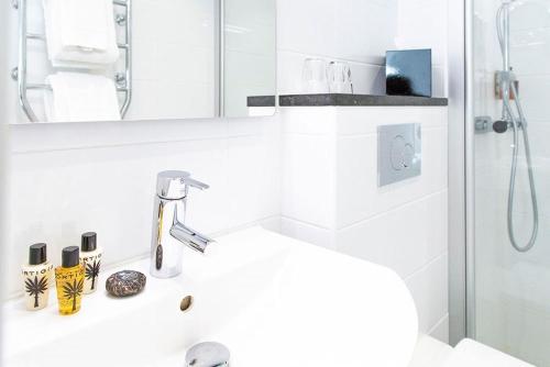 a white bathroom with a sink and a shower at Continental du Sud in Ystad