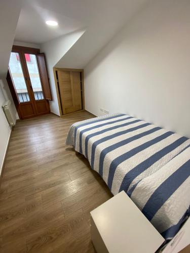 1 dormitorio con 1 cama con manta de rayas azul y blanco en El Capricho, en Siero