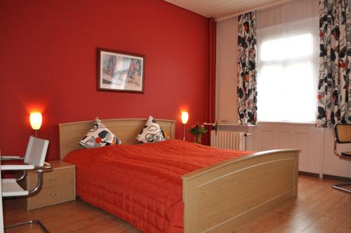 Dormitorio rojo con cama, escritorio y ventana en Hotel Restaurant Krone, en Wolfach