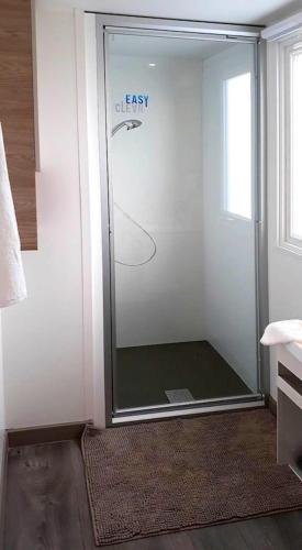 une douche avec une porte vitrée dans une salle de bain dans l'établissement Bungalow convivial à Saint-Brevin-les-Pins avec piscine - 32 m², à Saint-Brévin-les-Pins