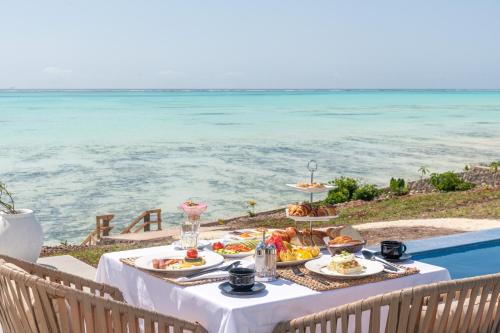 a table with food on it next to the ocean at Villa Bluu Zanzibar in Jambiani