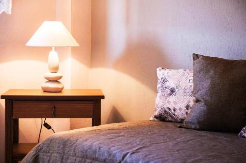 a bed with a table with a lamp on it at Nea Roda Apartments in Nea Roda