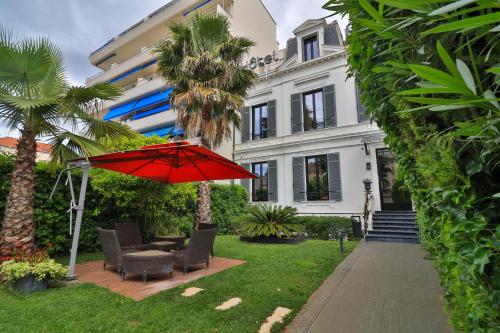 eine Terrasse mit einem roten Regenschirm vor einem Haus in der Unterkunft Villa Pruly Hotel Cannes Centre in Cannes