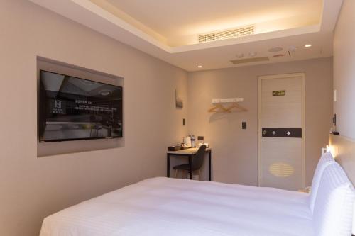 um quarto com uma cama branca e uma televisão de ecrã plano em 旅居文旅板橋驛站-湳雅夜市館Hub Hotel Banqiao inn-Nanya Night Market Branch em Taipei