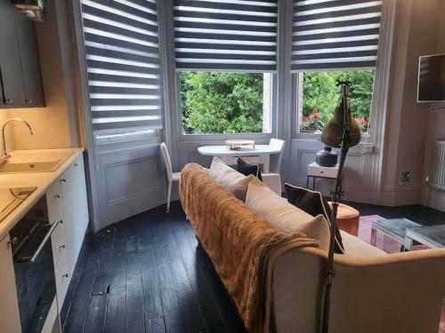 een woonkamer met een bank en 2 ramen bij 9 Modern Classic - Spacious One Bed Apartment - Great Location - Free onsite Parking - Comfy Bed in Brighton & Hove
