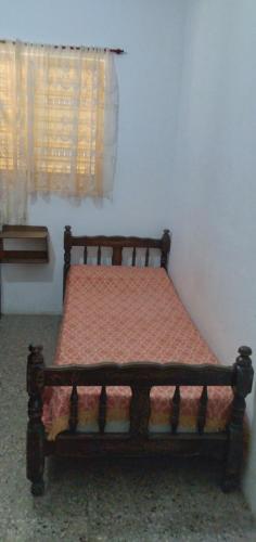 a wooden bed in a room with a window at Casa Low Cost 7 personas in Mina Clavero