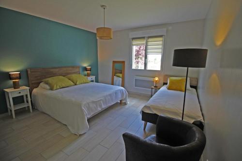 1 dormitorio con 2 camas y 1 silla en Les cypres, en Magnac-Bourg