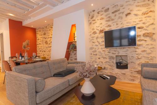 un salon avec un canapé et une télévision sur un mur dans l'établissement Lovely Apartment, heart of Paris center, à Paris