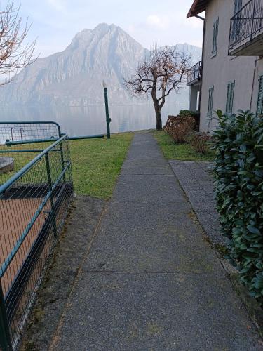 a sidewalk next to a building with a mountain in the background at Studio Zu - Lakeside Apartment in Riva di Solto