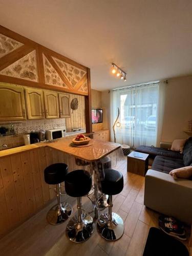 une cuisine et un salon avec une table et des chaises dans l'établissement La Féessence boisée Le Mont Dore, à Le Mont-Dore