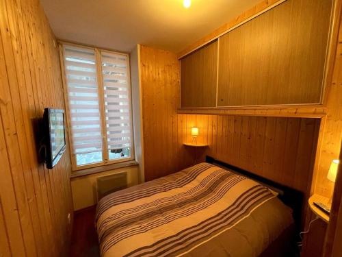 une petite chambre avec un lit et une fenêtre dans l'établissement La Féessence boisée Le Mont Dore, à Le Mont-Dore