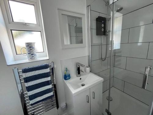 biała łazienka z umywalką i prysznicem w obiekcie Rainbow Cottage w mieście Helston