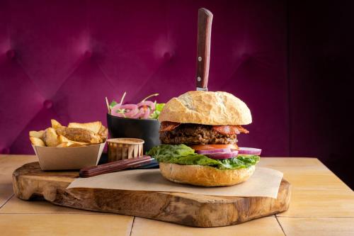 a sandwich on a wooden cutting board with fries at Hoeve de Binnenplaets Schimmert in Schimmert
