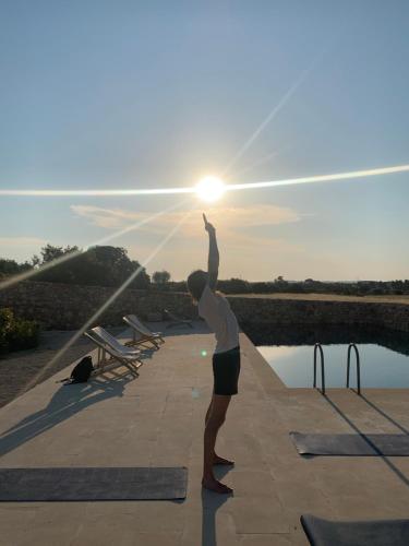 a man standing on a patio holding the sun at Masseria Caposella in Ugento