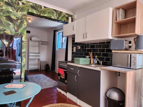 een keuken met een fornuis, een wastafel en een tafel bij Trendy Johannesburg Cottages in Johannesburg