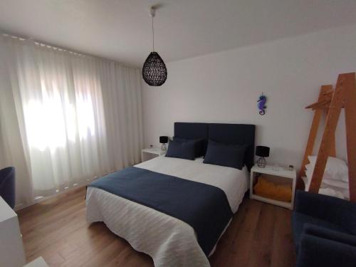 a bedroom with a large bed with blue and white sheets at Silver Home in Nazaré