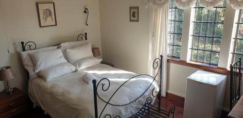 a bedroom with a bed with white sheets and windows at The Sleeping Bao B&B in Pietermaritzburg
