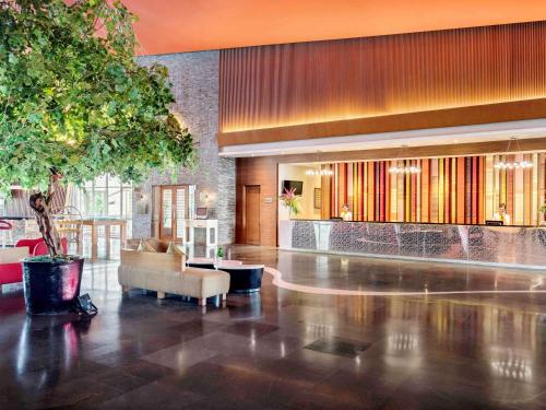 een lobby met een bank en een tafel in een gebouw bij Novotel Palembang in Palembang