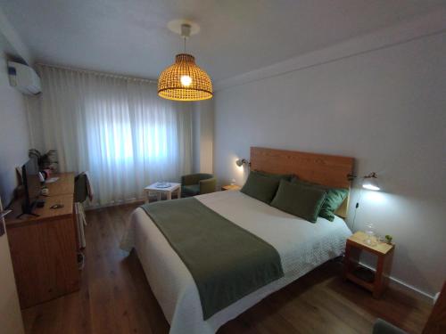 - une chambre avec un grand lit et une lampe pendant dans l'établissement Silver Home, à Nazaré