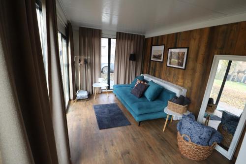 sala de estar con sofá azul y paredes de madera en Pałac Rozkochów -Domki Hrabiego- domek 2, 