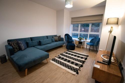 a living room with a blue couch and a table at Moseley Gardens Fallowfield in Manchester