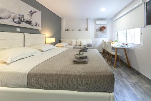two beds in a bedroom with a table and a desk at Comfort Stay Airport Studios - FREE shuttle from the Athens airport in Spata