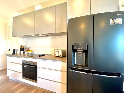 a kitchen with a black refrigerator and white cabinets at Wamoon Retreat - Luxe House in Yanakie