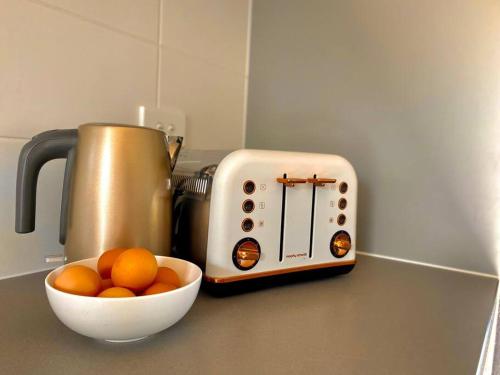 a counter with a bowl of oranges next to a toaster at Wamoon Retreat - Luxe House in Yanakie