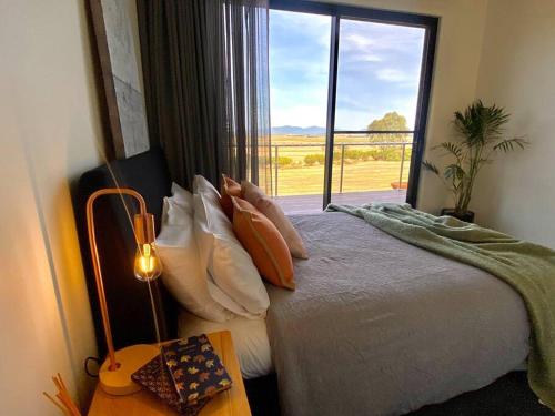 a bedroom with a bed and a large window at Wamoon Retreat - Luxe House in Yanakie
