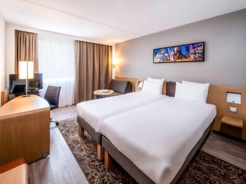 a hotel room with a large bed and a desk at Novotel Rotterdam - Schiedam in Schiedam