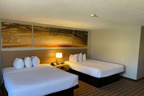 a hotel room with two beds and a painting on the wall at Days Inn by Wyndham Fayetteville-South/I-95 Exit 49 in Fayetteville