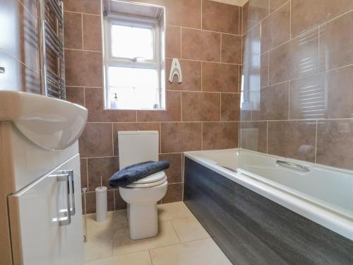 a bathroom with a toilet and a tub and a sink at 3 Wilson Cottages in Ganton