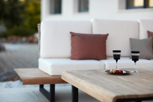 a table with two wine glasses and a plate of food at Villa The Longhouse- Pool-Sauna-Gym- Panormaic Seaview in Sellía