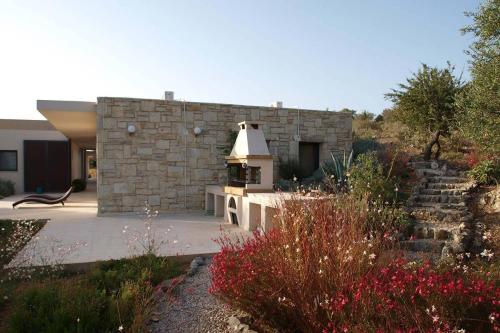 a garden with a stone building with a grill at Villa The Longhouse- Pool-Sauna-Gym- Panormaic Seaview in Sellía