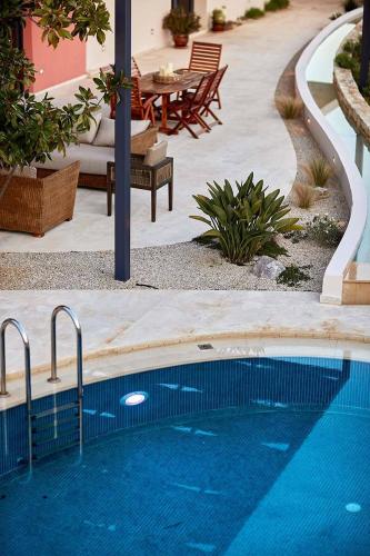 a swimming pool in a courtyard with a table and chairs at Villa The Longhouse- Pool-Sauna-Gym- Panormaic Seaview in Sellía
