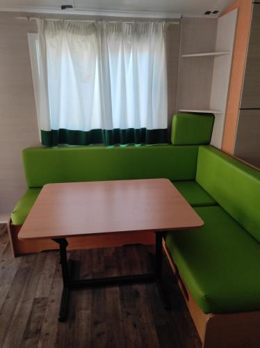 a table and a green couch in a room at Bungalow Tossa Pelada i Mobil Home Rodell in Fornols