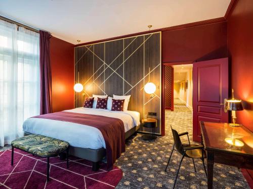 a hotel room with a large bed and a desk at Aigle Noir Fontainebleau MGallery in Fontainebleau