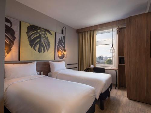 a hotel room with two beds and a window at ibis Santa Cruz de la Sierra in Santa Cruz de la Sierra