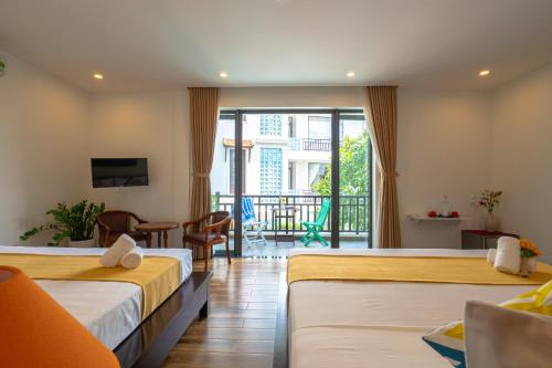 a hotel room with two beds and a balcony at Golden Star Villa Hoi An in Hoi An