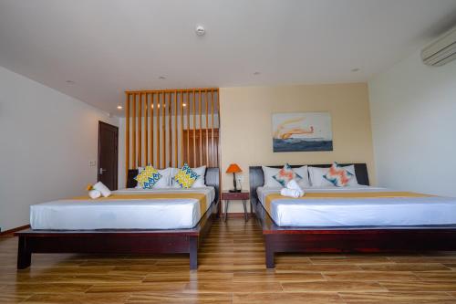 two beds in a room with wooden floors at Golden Star Villa Hoi An in Hoi An
