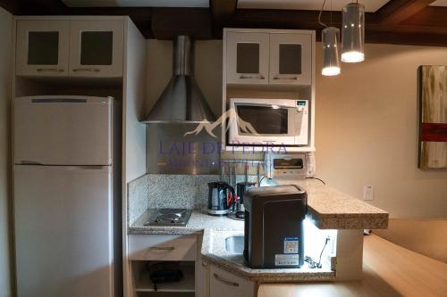 a kitchen with a white refrigerator and a microwave at Laje de Pedra Mountain VillagePrime in Canela