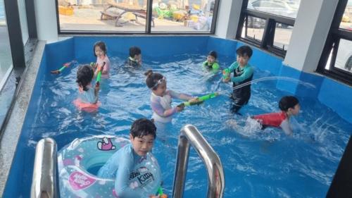 un grupo de niños jugando en una piscina en Storm Wind Poolvilla, en Ulsan