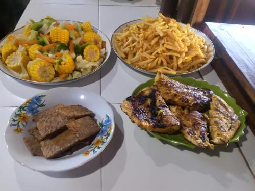 three plates of food on a table with different foods at Home stay wolokoro ecotourism in Bajawa